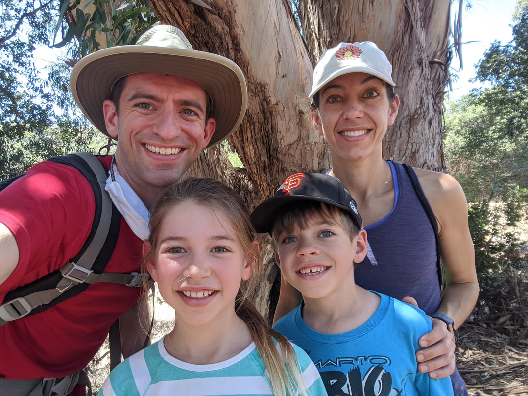 Close up selfie of Salvia family (Jim, Melanie, Wes, and Kim) smiling at the camera in front of a large tree.